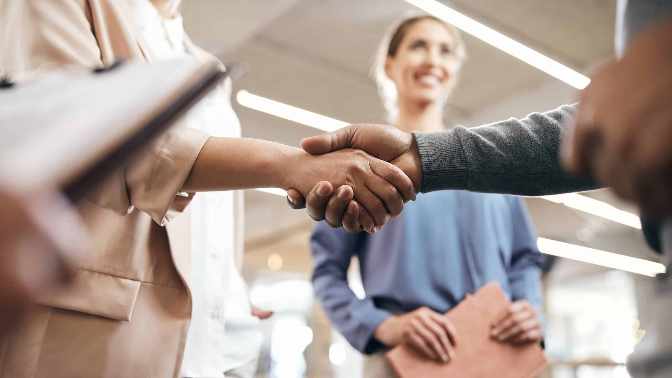 Two people shaking hands across a table